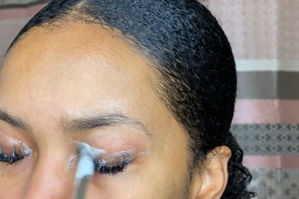 an african women is cleaning her brows from estetist eye lash extension cleanser 