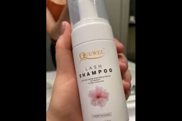 white bottle hold in hand of quewel lash shampoo 